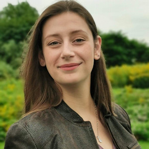 Professional headshot of Calandra Van Massenhoven in front of a nature background.