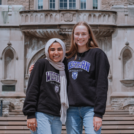 Two students in Western clothing stand together on campus
