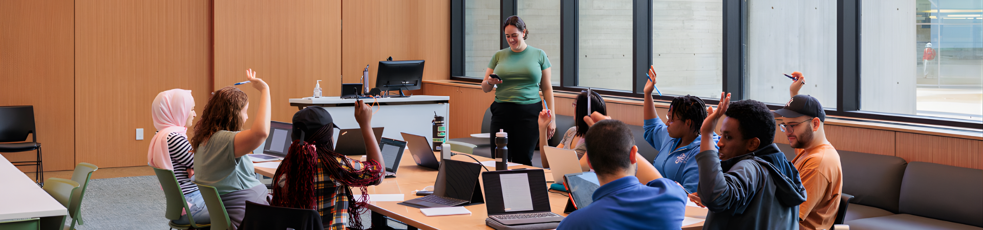 Several people sit around a long table, each raising a hand to show their agreement.